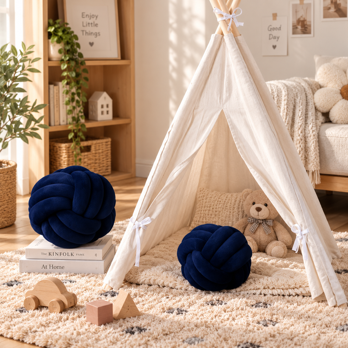 HavvakHome navy blue knot ball pillows styled inside and beside a cream teepee play tent on a plush rug.