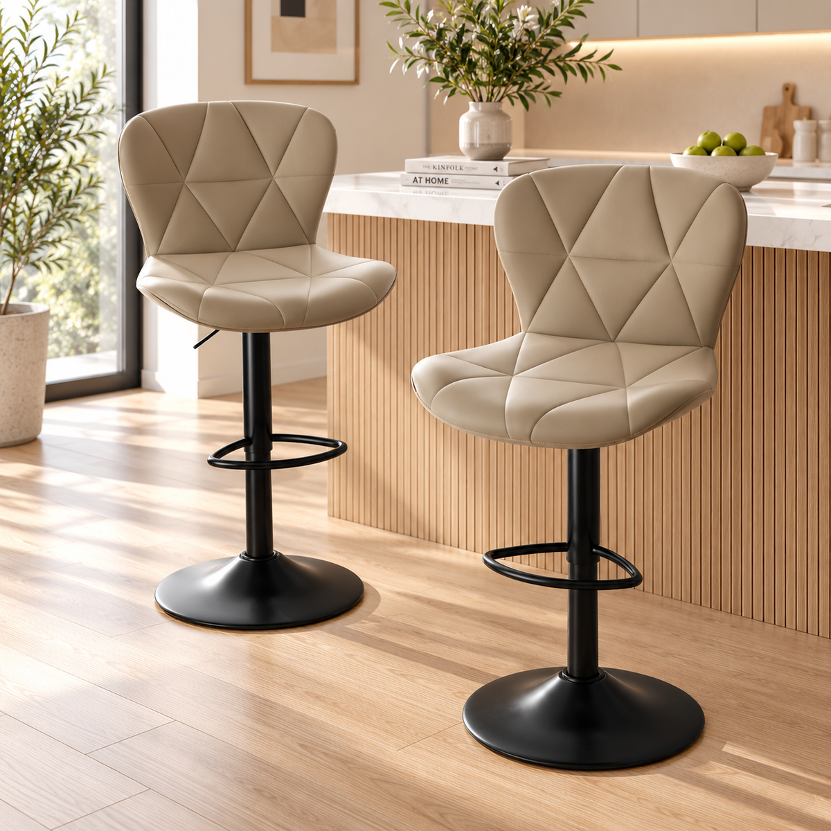 Two beige quilted bar stools with black pedestal bases and footrests styled beside a wood slatted kitchen island in a sunlit room by HavvakHome.