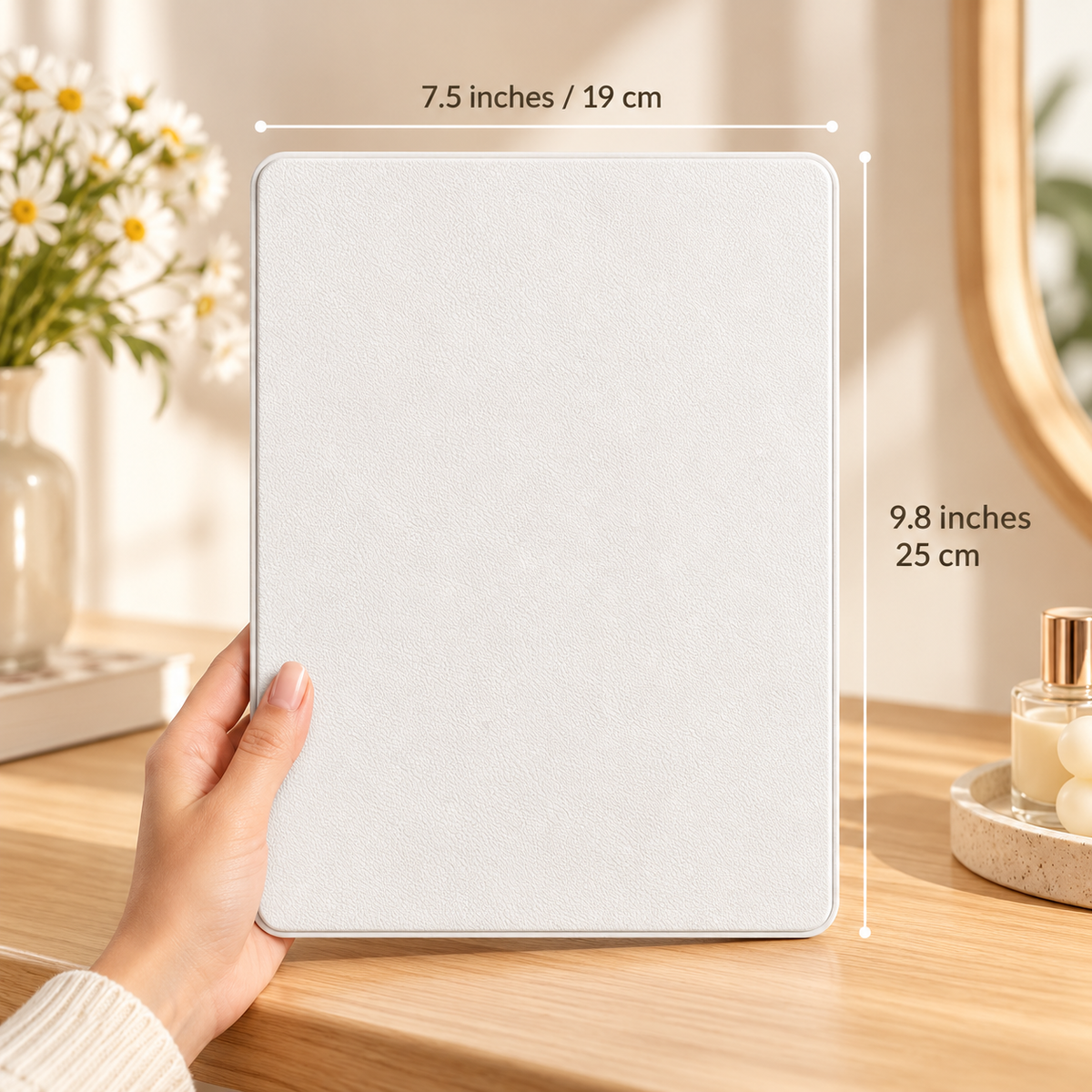 Hand holding a closed white travel mirror cover upright on a wood vanity with dimension lines showing 7.5 inches / 19 cm width and 9.8 inches / 25 cm height by HavvakHome.