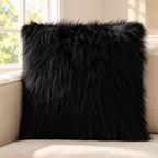 black long-pile faux fur pillow cover on a beige sofa beside a bright window.