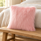 pink long-pile faux fur pillow cover on a wooden bench at the foot of a cream linen bed.