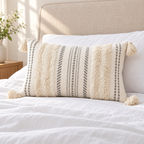 Beige and cream white 20x12 lumbar tufted pillow cover on a white bed with beige headboard.