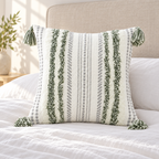 Green and cream white square tufted pillow cover with fluffy tufting on a white bed.