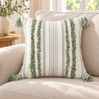 Green and cream white square boho tufted pillow cover with tassels on an oatmeal sofa.