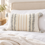 Light grey and cream white 20x12 lumbar tufted pillow cover on a white bed with beige headboard.