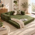 Olive green corduroy modular sofa bed extended flat in a sunlit living room with metal side rails, checkerboard and knot pillows, cream knit throw, and an open book by HavvakHome.
