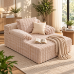 Cream faux rabbit fur cloud chaise with padded arms, cream pillow, open book, and knit throw at right front, with plants and a wood side table by a window by HavvakHome.