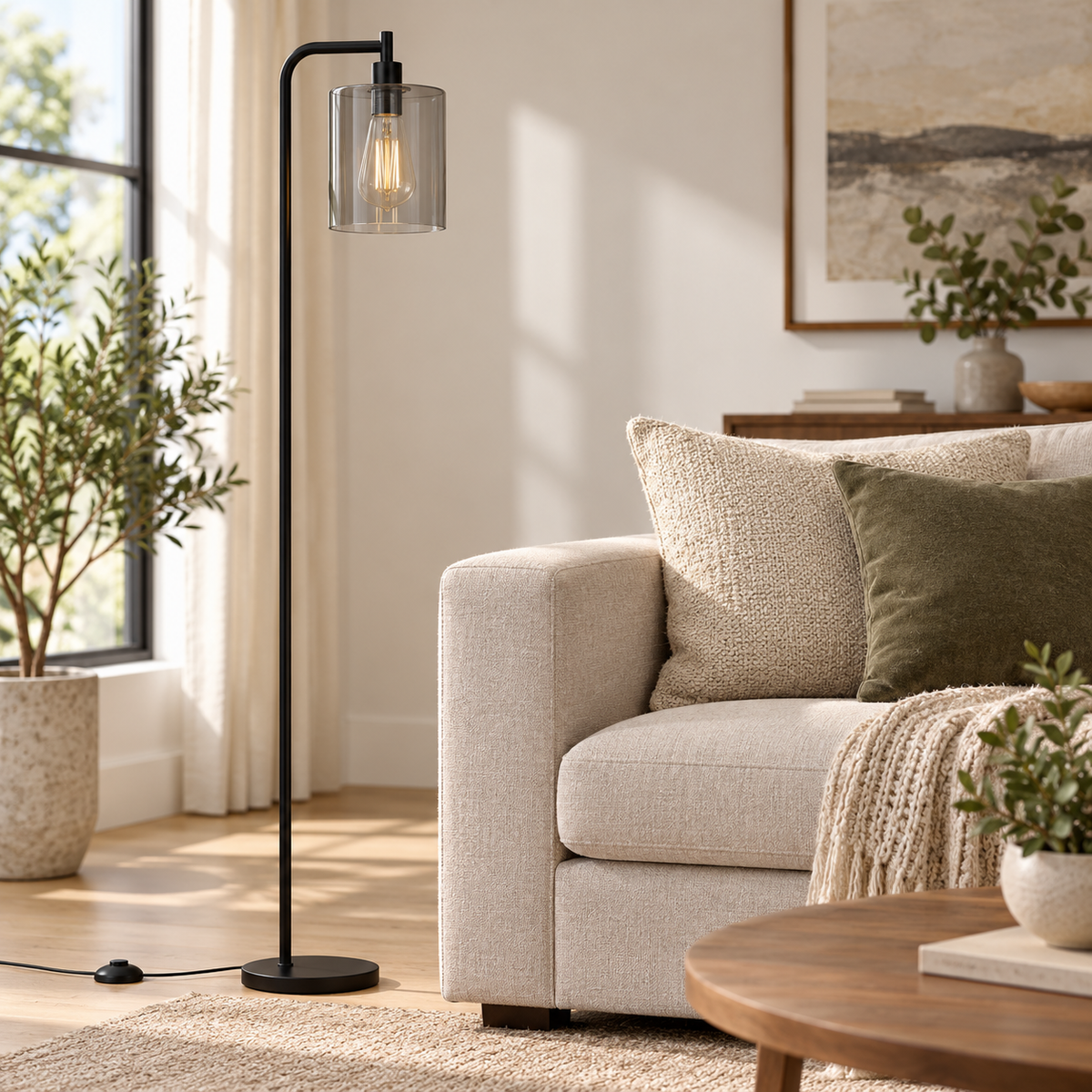 Smoke-grey cylindrical glass black floor lamp beside a beige sofa in daylight.