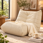 Cream button-tufted armless floor lounge chair with cream knitted throw on a rug beside a wood side table in a sunlit living room by HavvakHome.