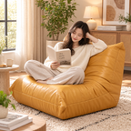 Woman reading a book while sitting cross-legged on a mustard yellow floor lounge chair in a sunlit living room by HavvakHome.
