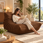 Woman reading barefoot on a brown tufted memory foam fireside chair beside a sunny window.