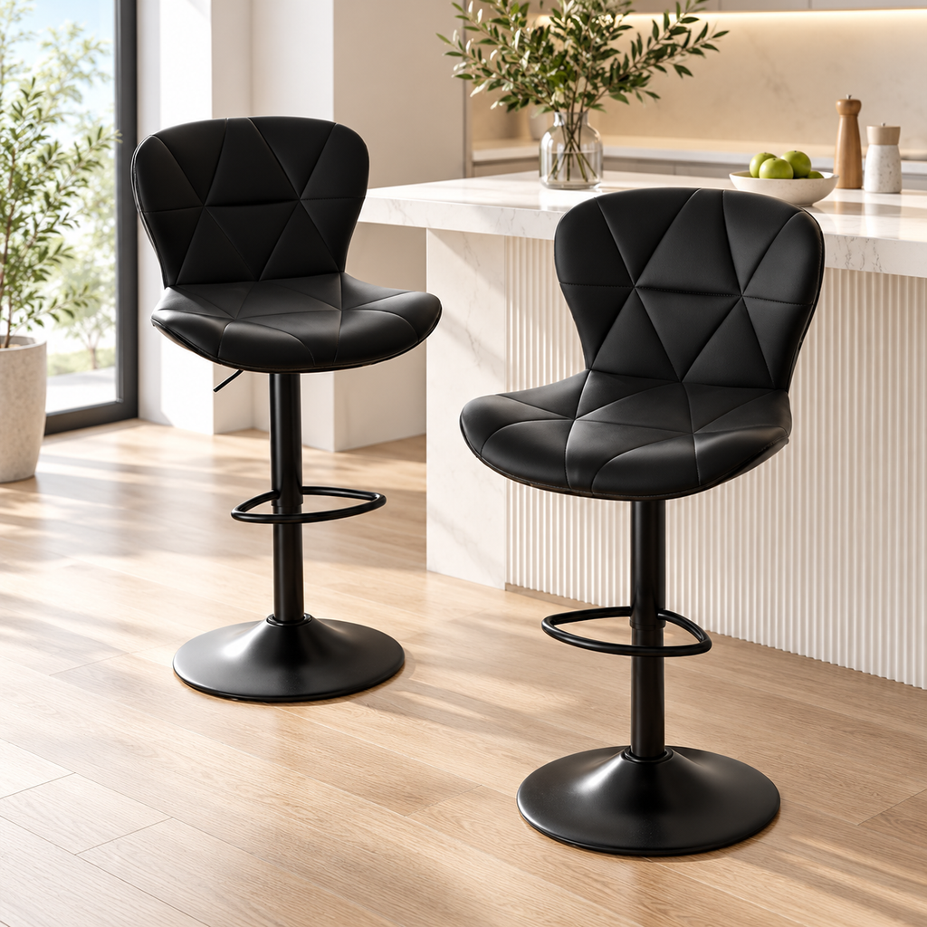 Two black quilted bar stools with black pedestal bases and footrests styled beside a light kitchen island by HavvakHome.