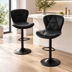 Two black quilted bar stools with black pedestal bases and footrests styled beside a light kitchen island by HavvakHome.