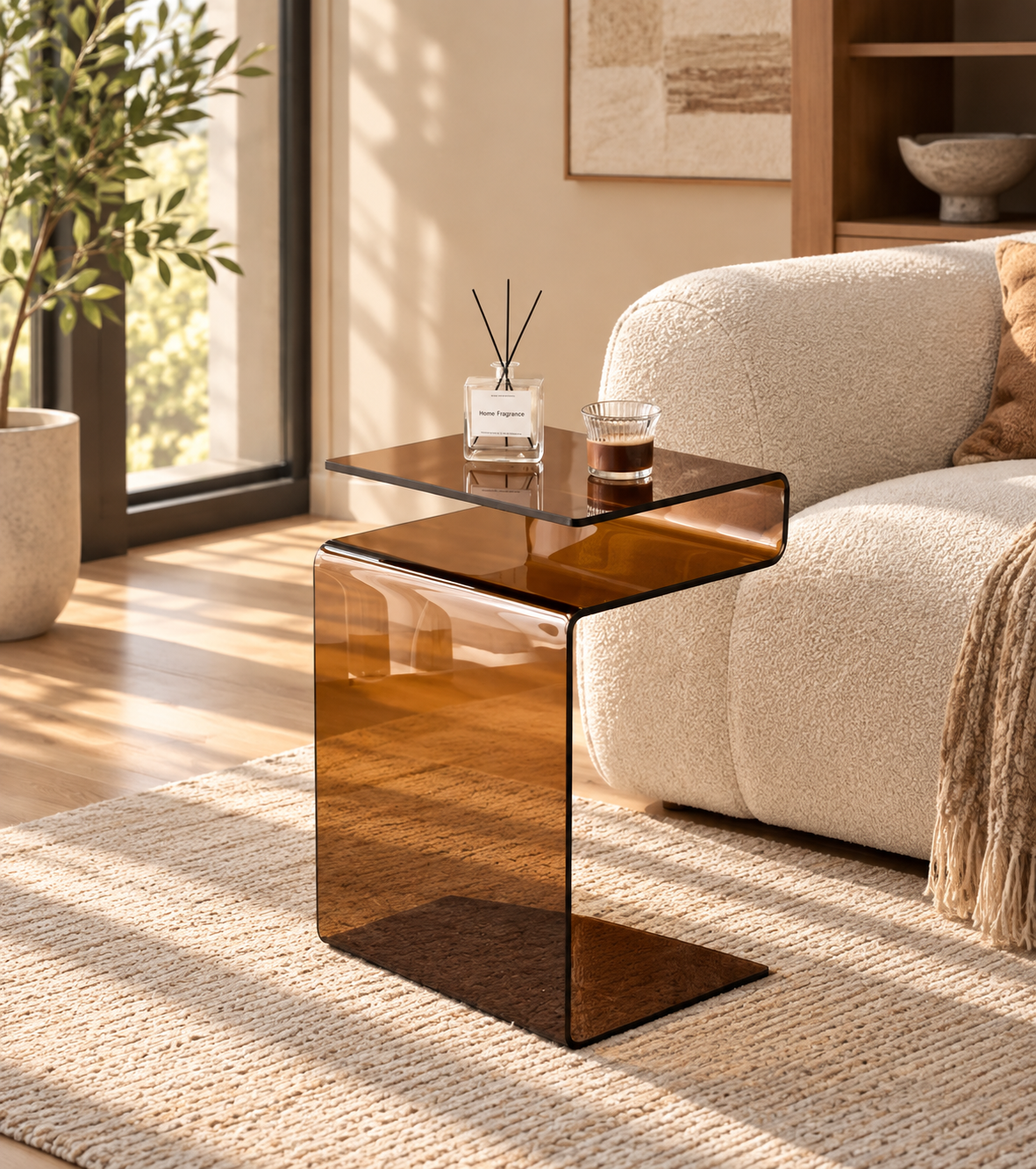 Amber S-shaped glass side table beside a cream armchair holding a coffee glass and reed diffuser by HavvakHome.