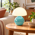 Blue ceramic mushroom lamp with a glossy rounded base and a white glass dome shade on wooden furniture in a naturally lit living room.