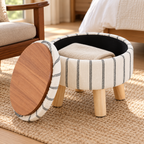 Black and white striped ottoman with lid unsealed leaning aside, showing wood-grain tray back and black storage interior on a bedroom rug.