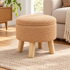 Champagne nubby fleece round storage ottoman with four light wood legs and closed lid beside an oatmeal sofa.