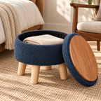 Dark grey-blue round ottoman with lid removed showing wood-grain underside and black interior with folded cloth.
