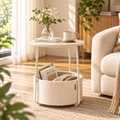 White round side table with a cream storage basket holding books and a blanket set beside a cream sofa, with a vase and mug on the tabletop by HavvakHome.