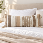 Brown 36x14 inch lumbar pillow cover with vertical woven stripes and corner tassels arranged on a white bed.