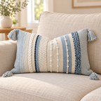 Coastal blue 20x12 inch lumbar pillow cover featuring vertical woven stripes, raised bobbles, and tassels on an oatmeal linen sofa.