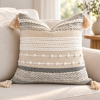 Gray 18x18 inch throw pillow cover with horizontal woven stripes, raised bobbles, and corner tassels on an oatmeal linen sofa.