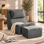 Dark gray corduroy lounge chair with matching pillow, ottoman, and cream throw beside a sunny window by HavvakHome.