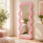 Pink wavy flannel-wrapped floor mirror leaning beside a dresser with pink tulips, reflecting a bed in a sunny bedroom.