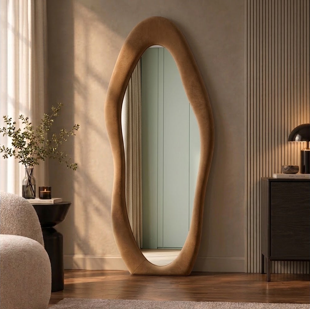 Tan brown wavy flannel-framed floor mirror leaning beside a wood-slat wall, reflecting a paneled doorway.